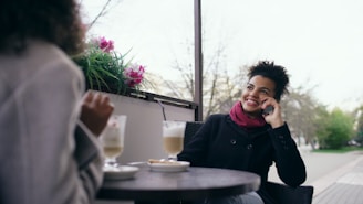 Two women talking and drinking at an outdoor cafe.