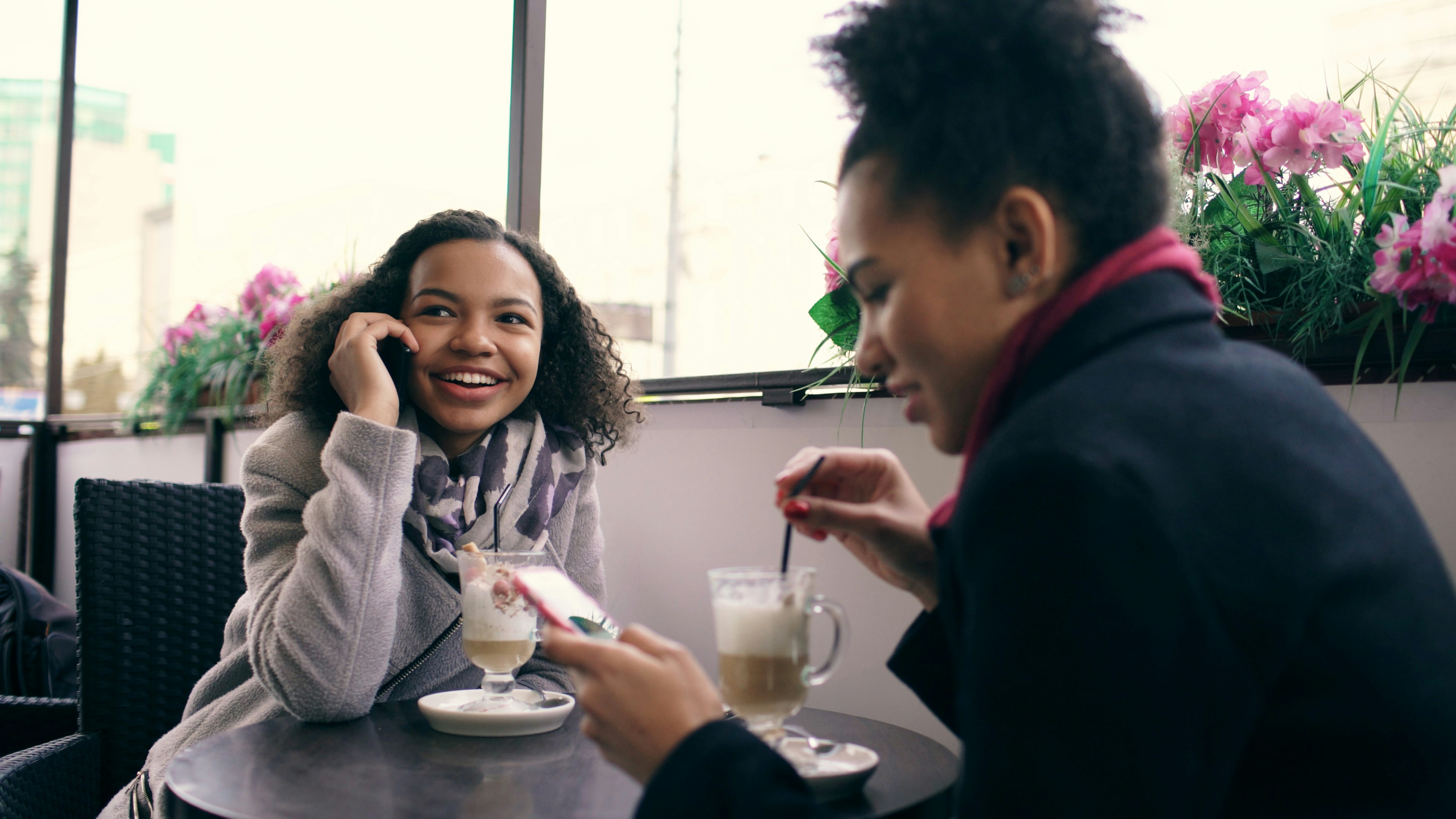 Two women talking and drinking coffee at a cafe.