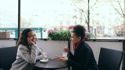 Two women talking at an outdoor cafe table.
