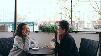 Two women talking at an outdoor cafe table.