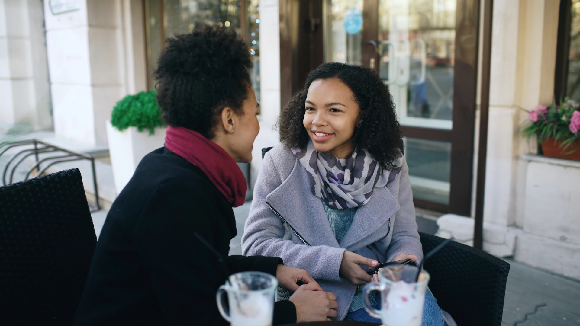 Two women talking at an outdoor cafe.