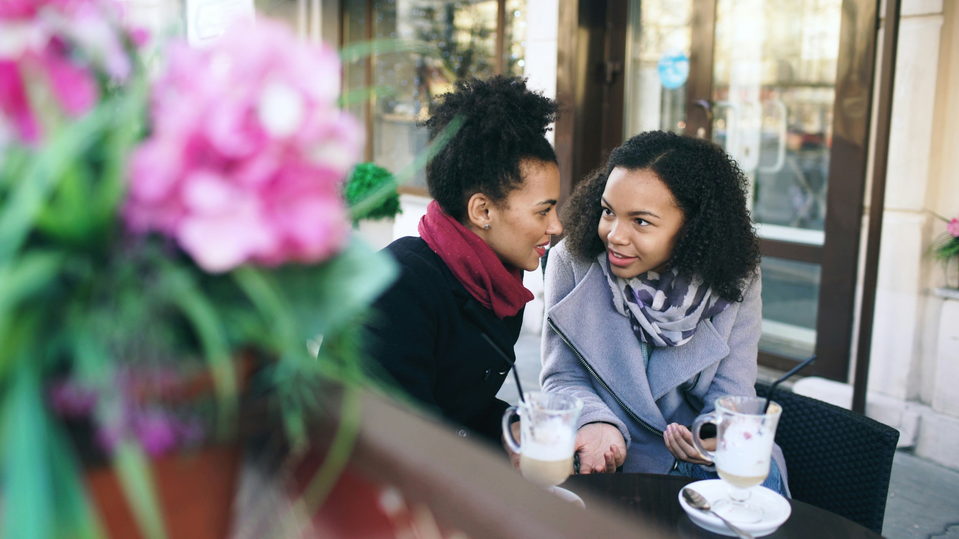 Two women talking at an outdoor cafe table.