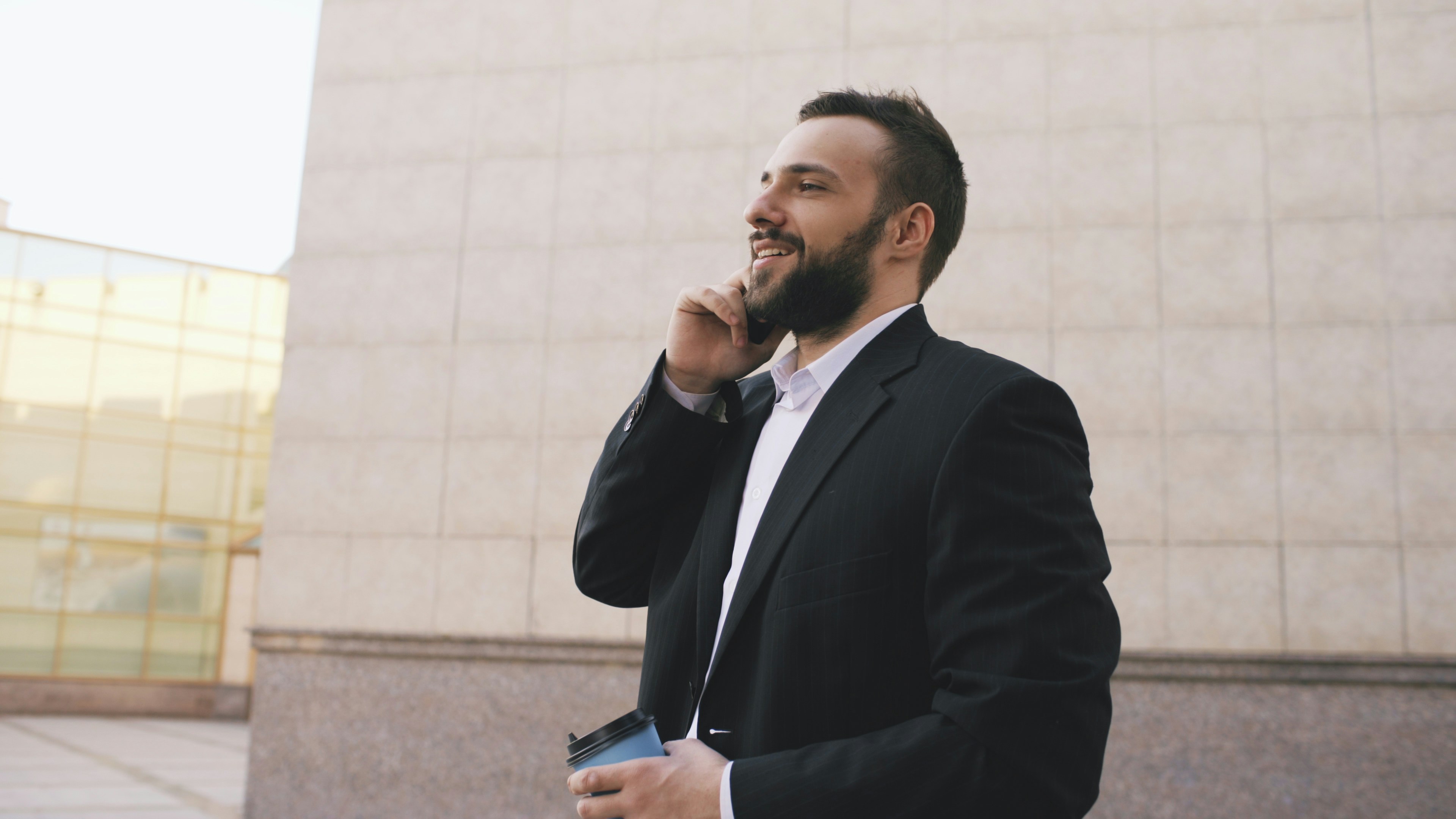 Man in suit talking on phone holding coffee cup
