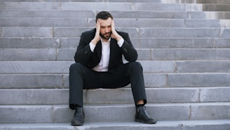 Man in suit sitting on stairs with head in hands
