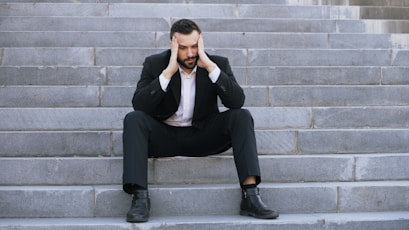 Man in suit sitting on stairs with head in hands