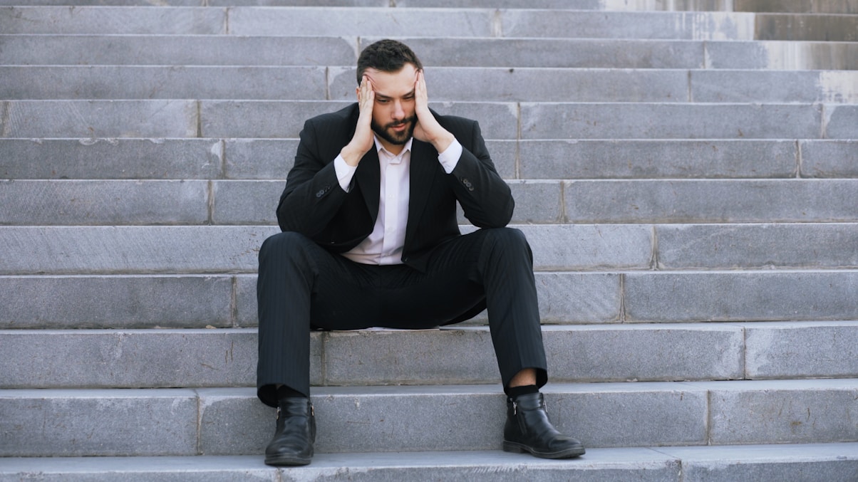 Man in suit sitting on stairs with head in hands