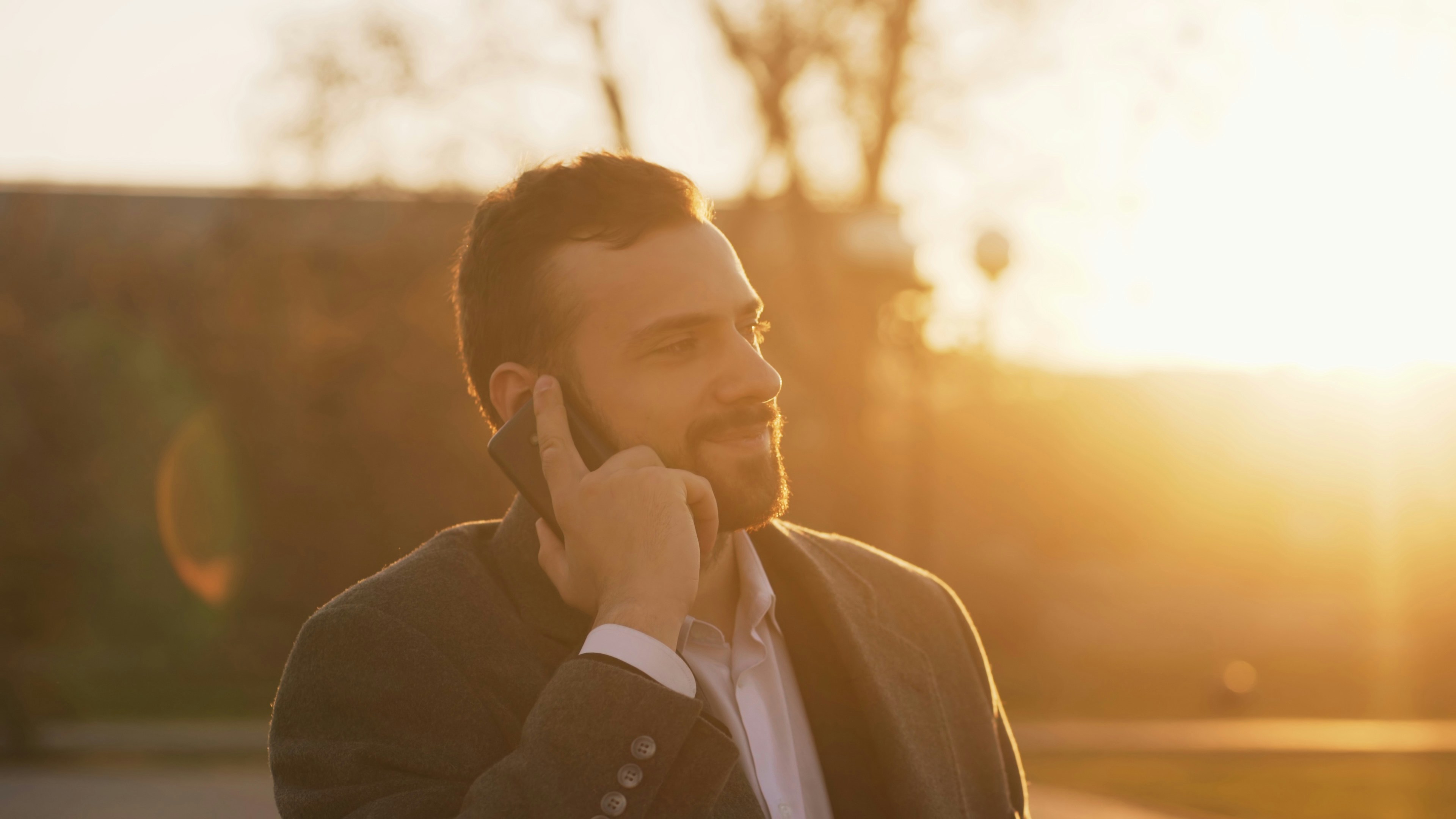 Man in suit talking on cell phone at sunset.