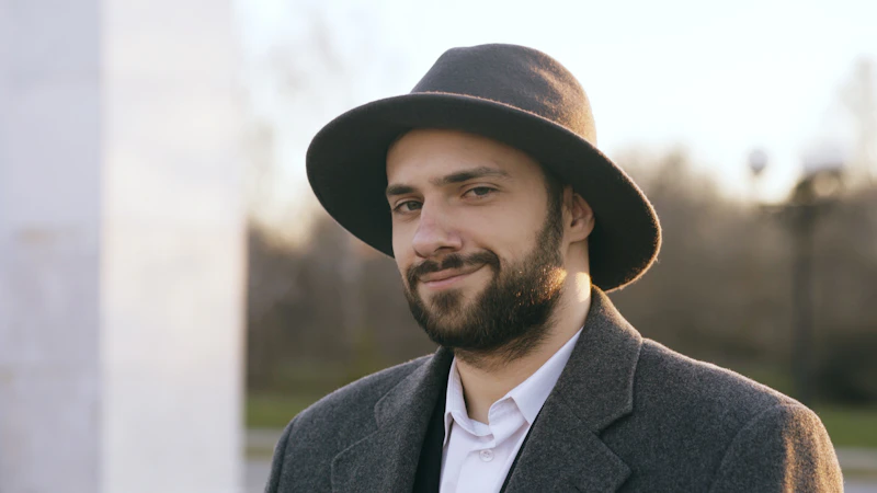 smiling man in a hat and coat outdoors