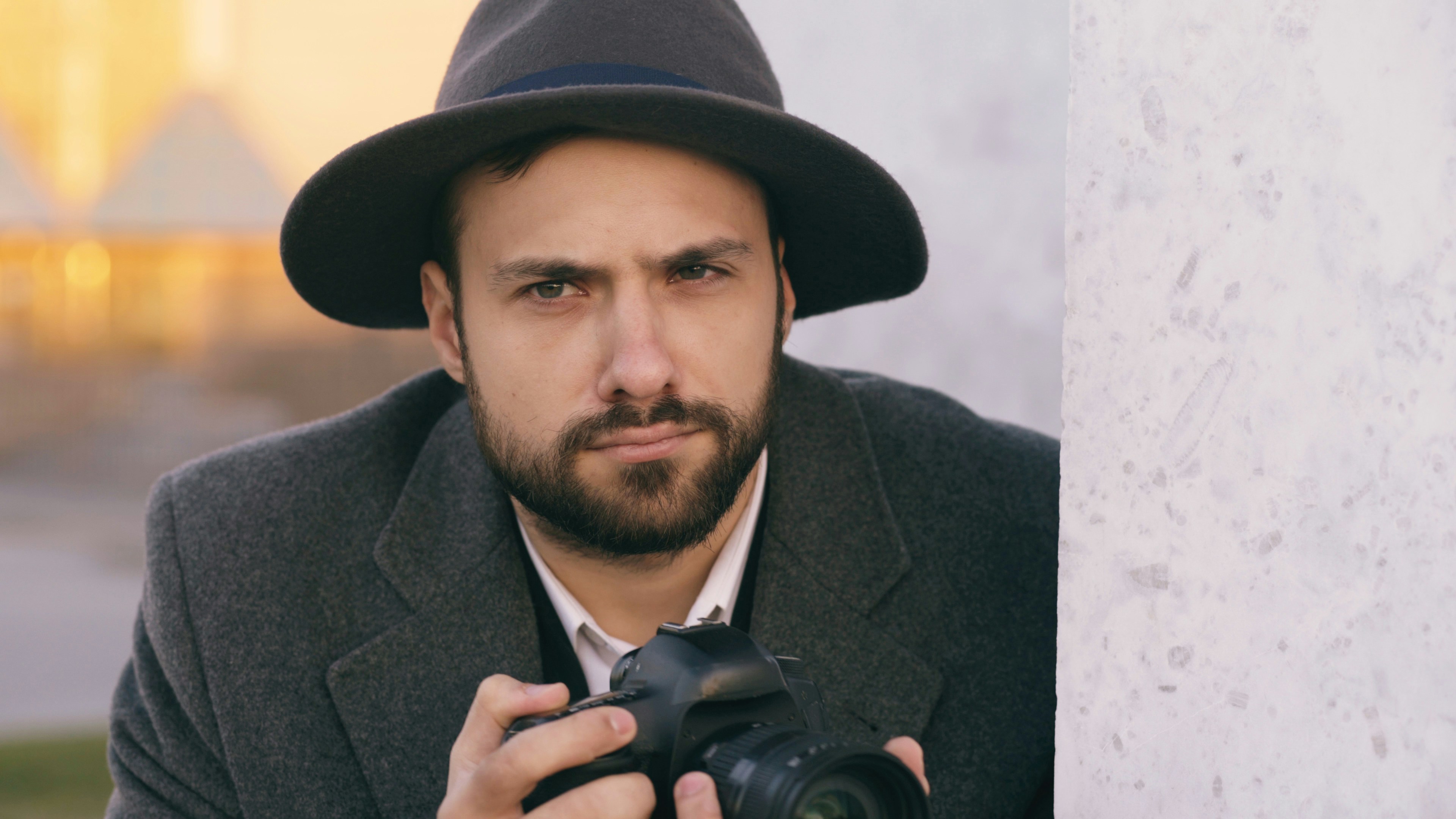 Man in hat holding a professional camera outdoors