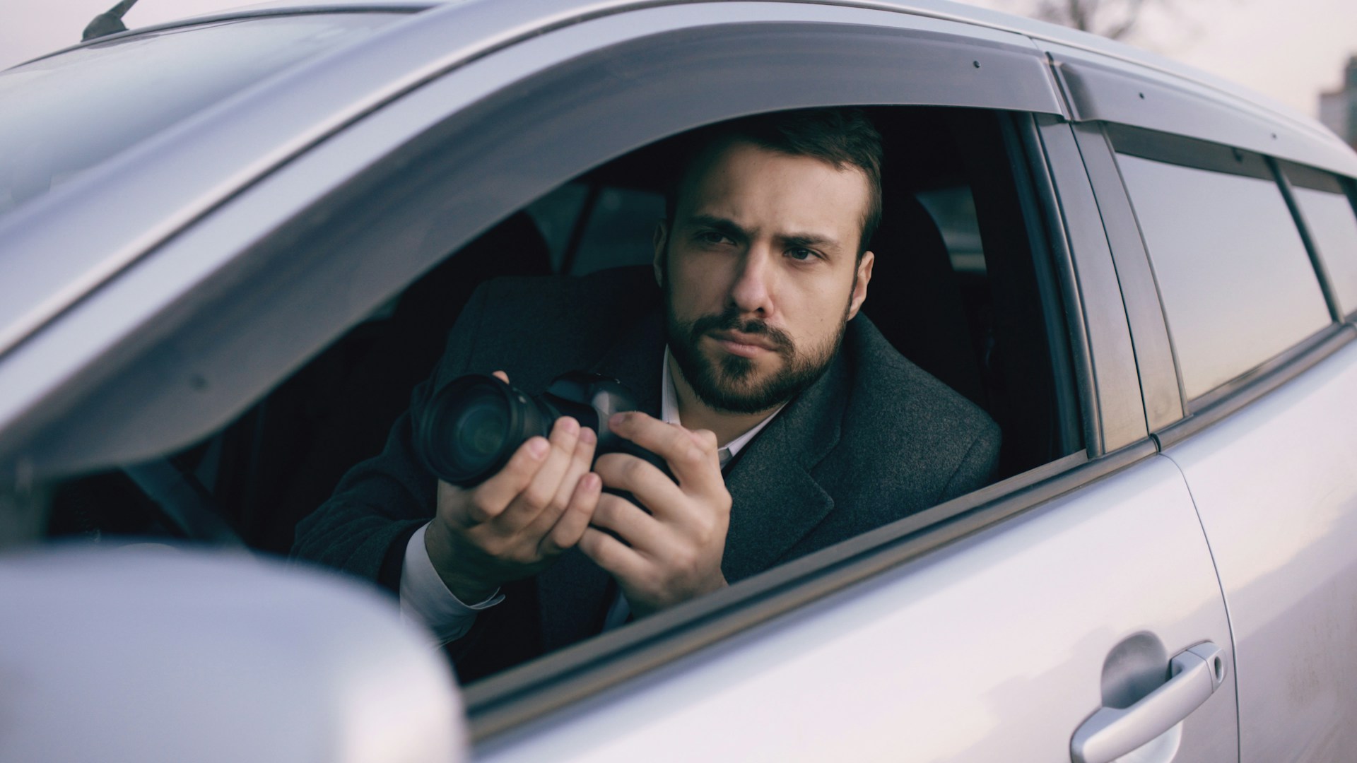 Man in car holding a camera lens