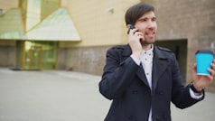 Joven profesional usando su smartphone con cafe cerca de una oficina en Malaga