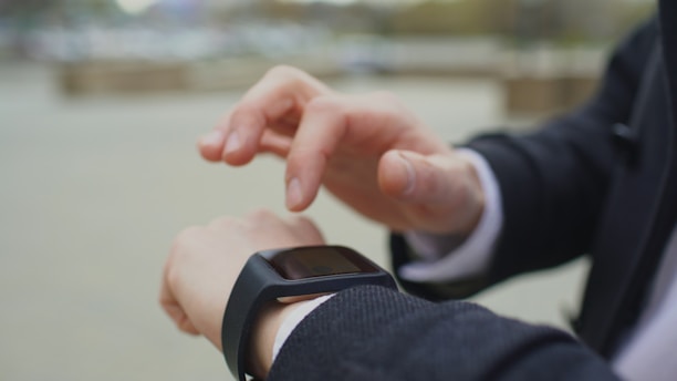 Man in suit checking smartwatch outdoors