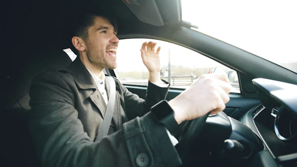 Man singing loudly while driving a car.