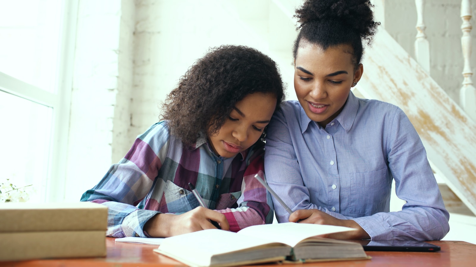 A parent and teenager working through schoolwork together at a table