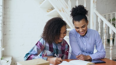 Two women smiling while studying at a table.
