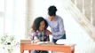 Mother helping daughter with homework at a desk.
