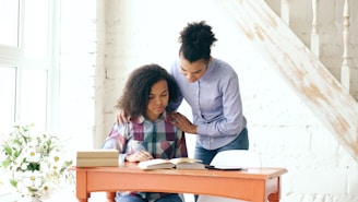 Mother helping daughter with homework at a desk.