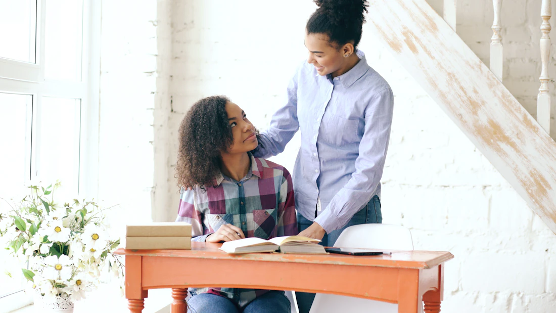 Two people working through a task together at a desk at home