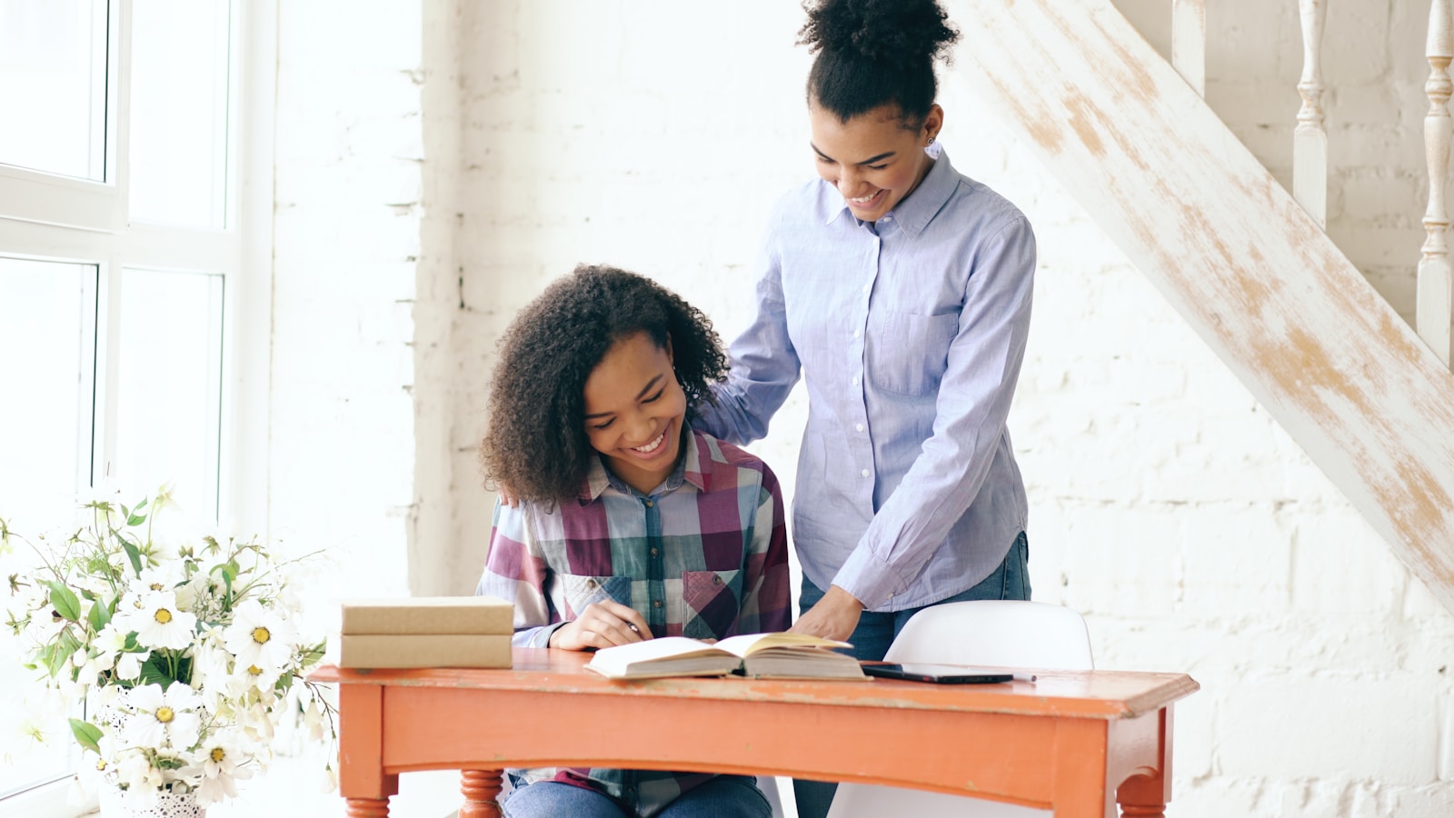 A teacher smiling as she works one-on-one with a student at a desk