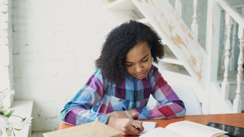 Young girl writing in a book at a table