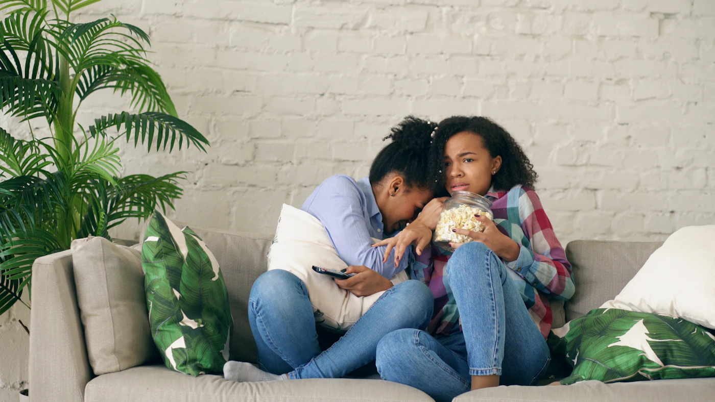 Two friends enjoying a movie night with popcorn at home