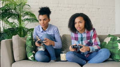 Two women playing video games on a couch.