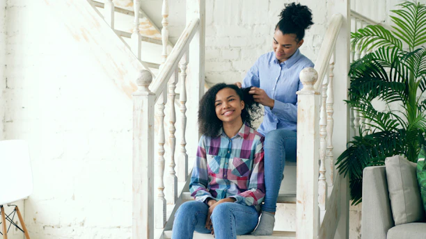 Mother braiding daughter's hair on staircase