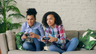 Two women playing video games on a couch.