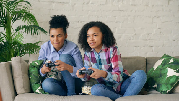 Two women playing video games on a couch.