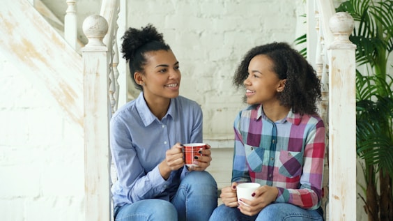 Two young women drinking coffee on stairs