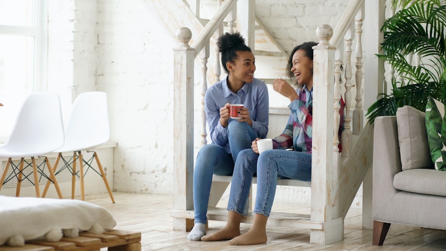 Two women laughing together while sharing coffee at home