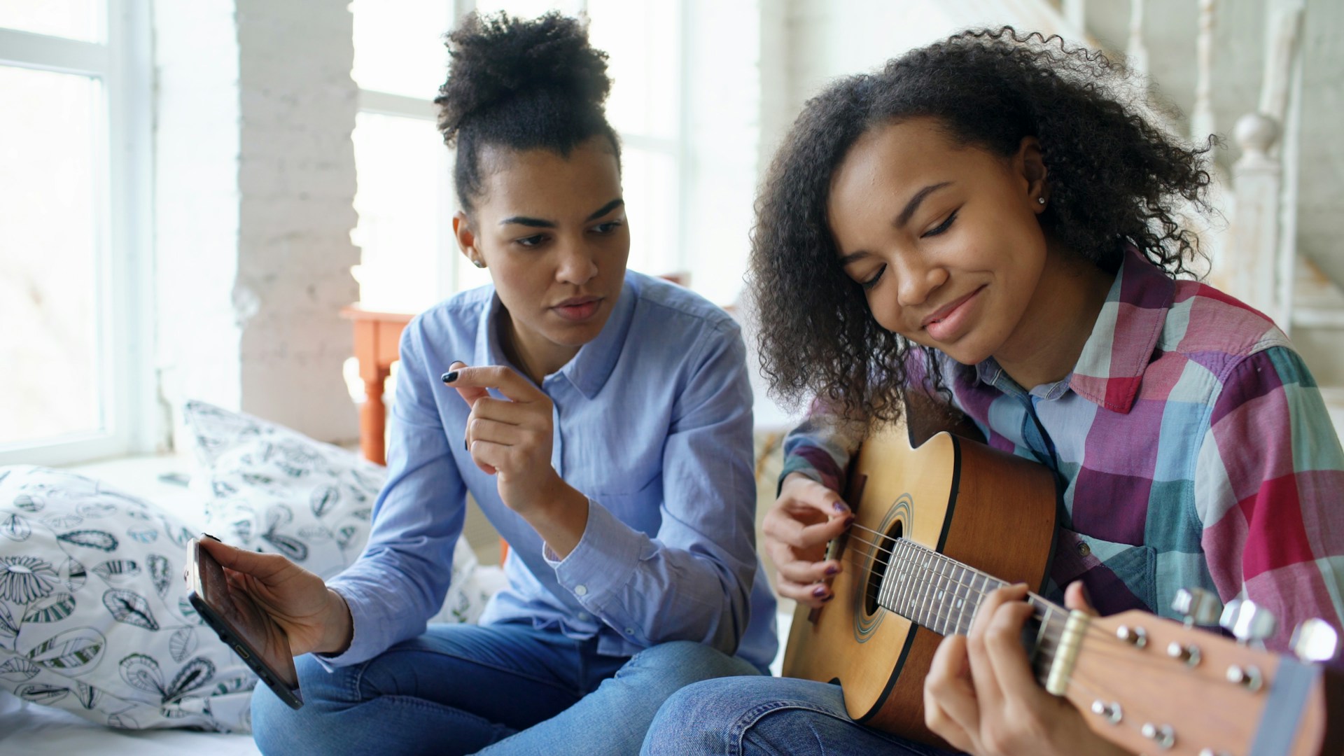 Two young women learning to play guitar together