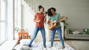 Two women singing and playing guitar at home