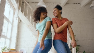 Two women dancing and laughing together indoors.