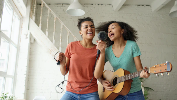 Two young women singing and playing guitar together