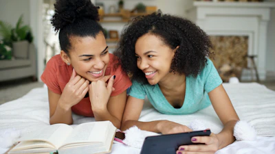 Two smiling young women looking at a smartphone
