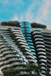 Modern building with curved balconies and lush greenery.