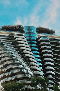 Modern building with curved balconies and lush greenery.