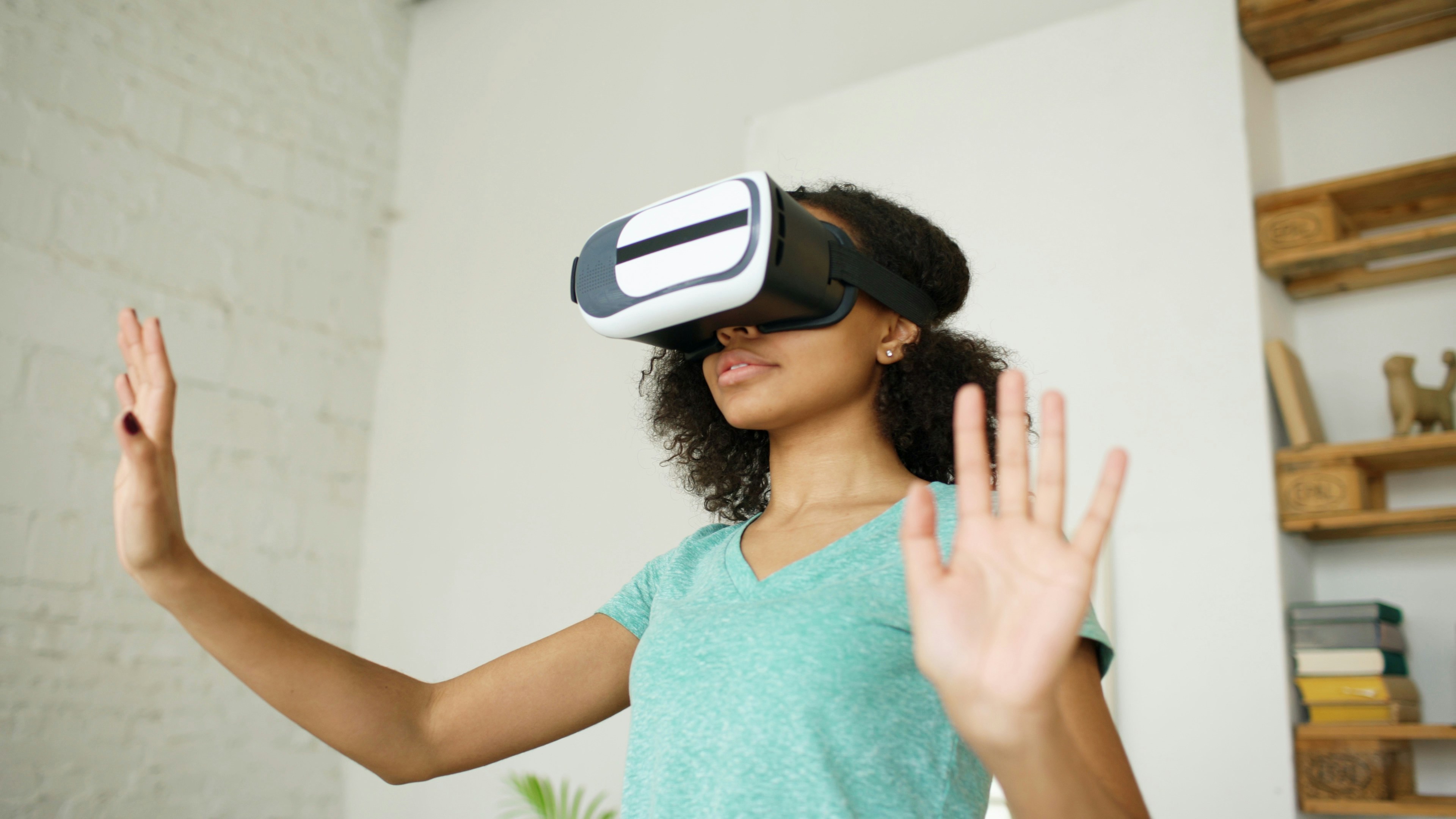 Young woman wearing vr headset, hands raised.
