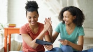 Two women high-fiving while looking at a tablet
