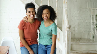 Two happy young women laughing together indoors