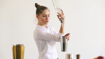 Bartender pouring liquid into cocktail shaker