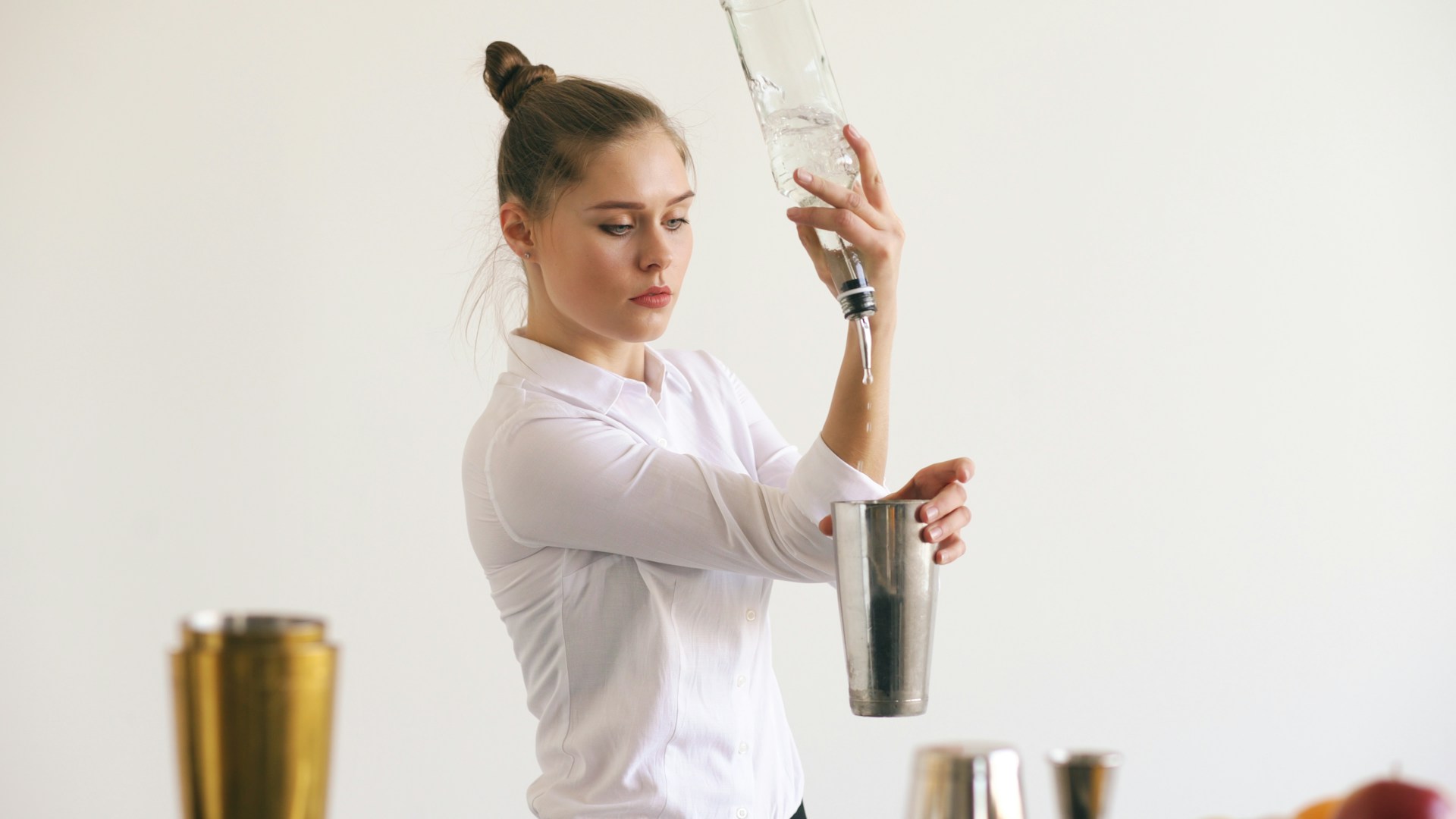 Bartender pouring liquid into cocktail shaker