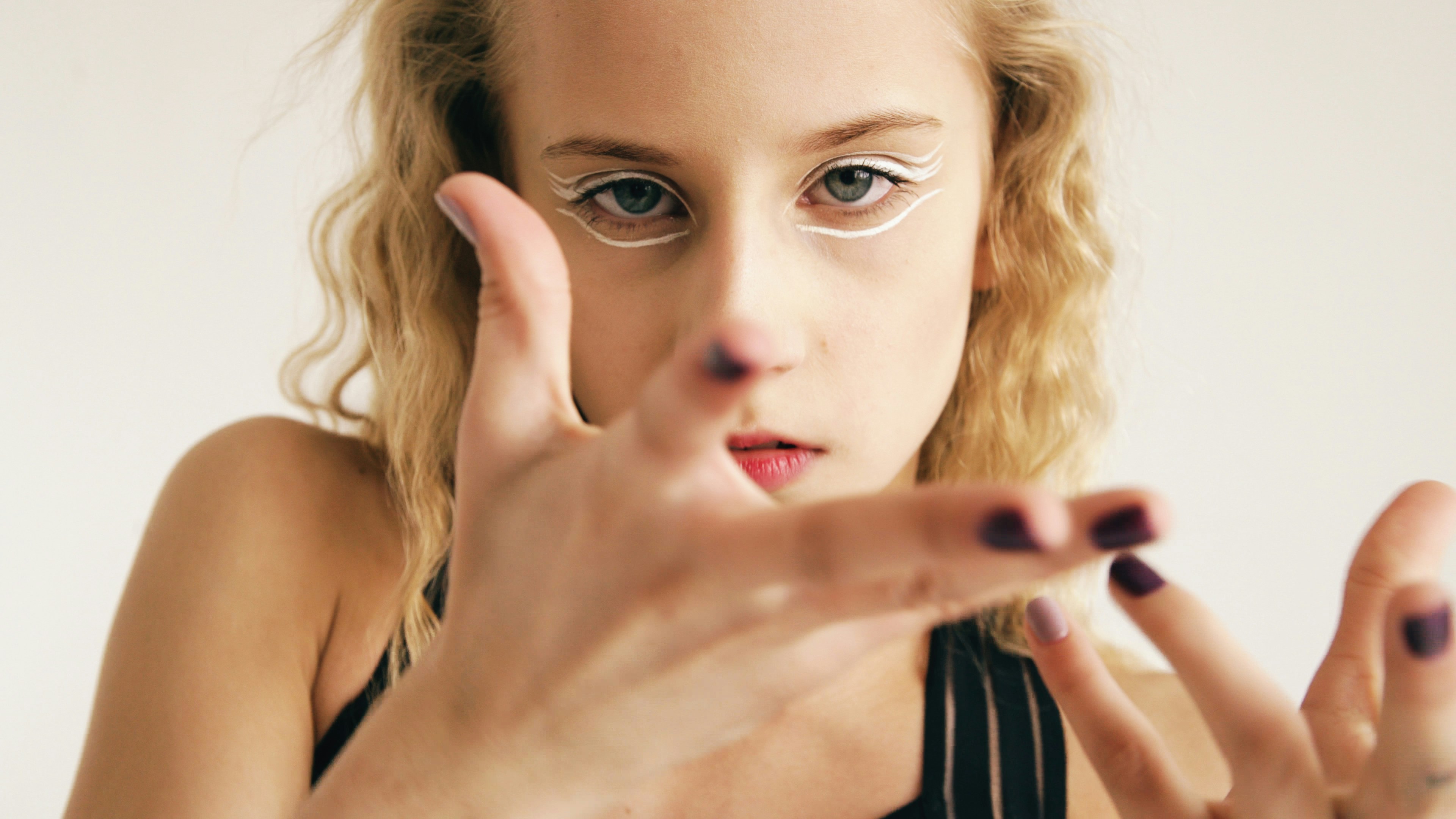 Young woman with white eyeliner and dark nails