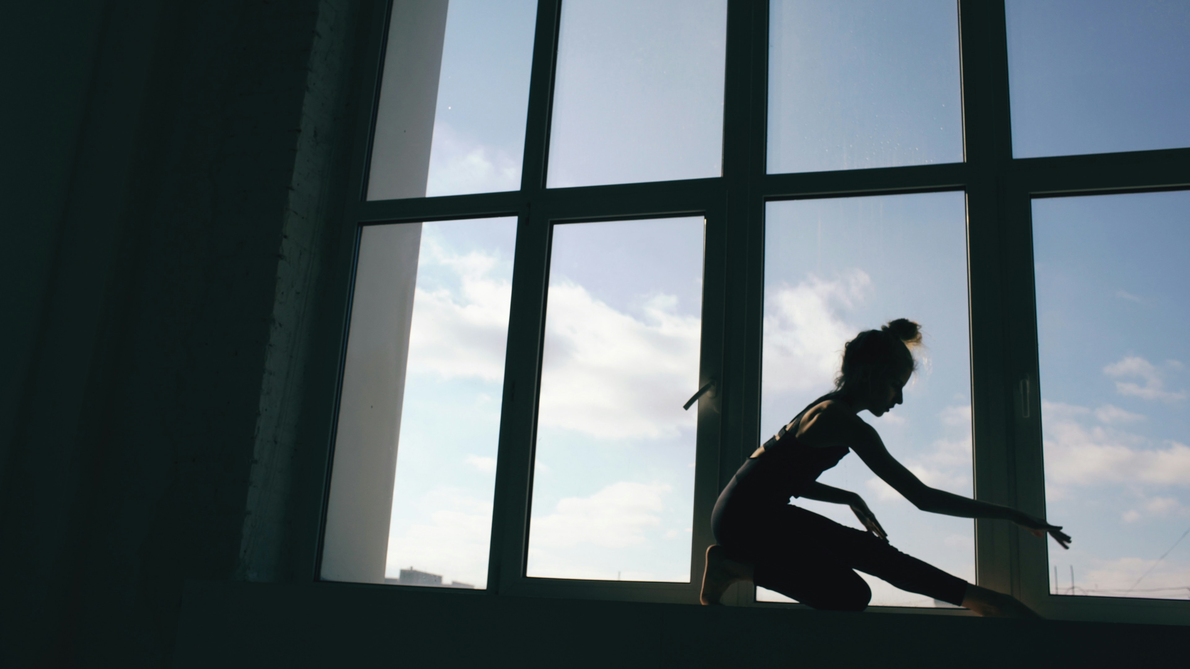 Silhouette of young girl dancer performance contemporary dance on windowsill in dance studio