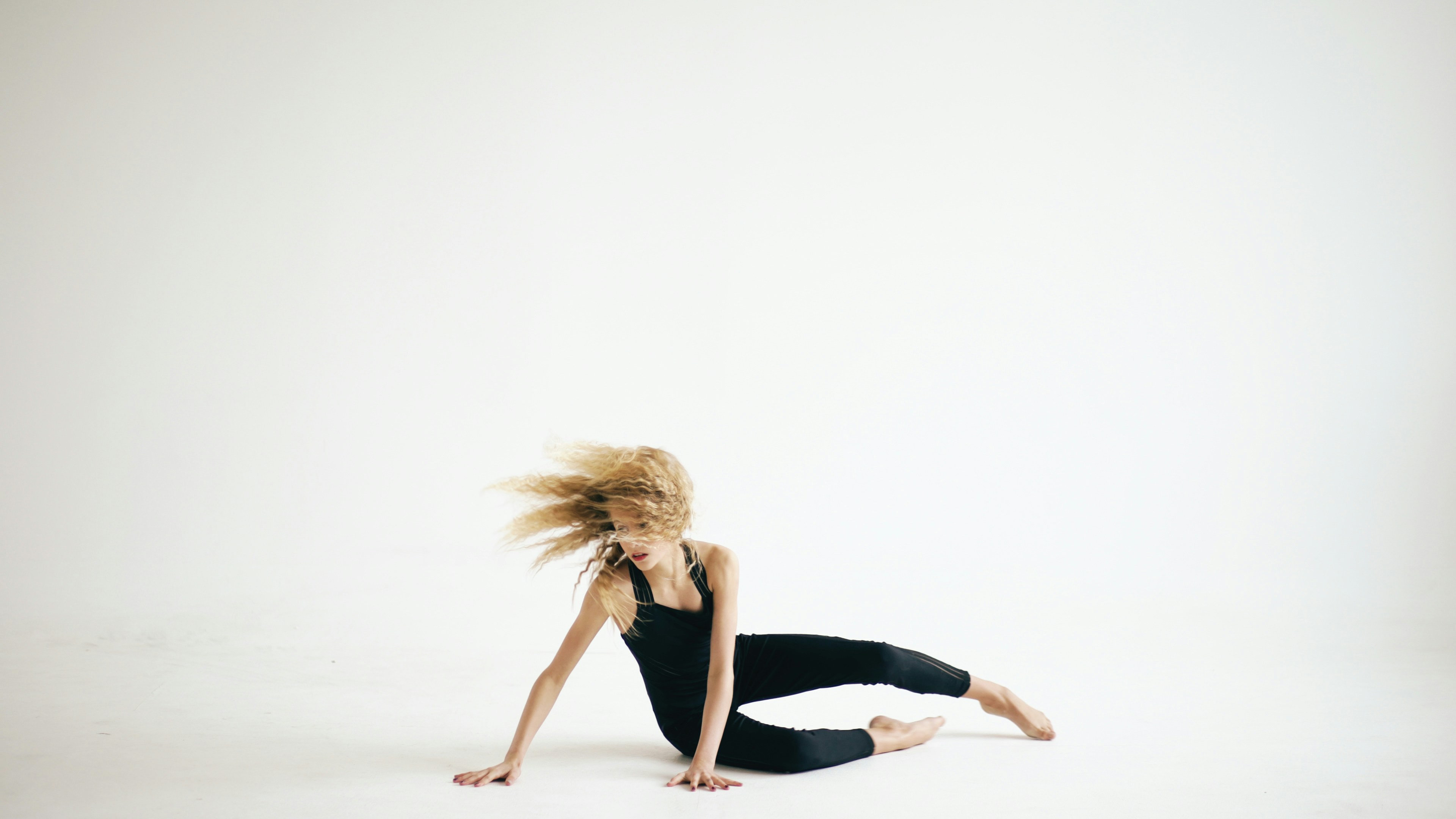 Blonde dancer in black leotard on white background