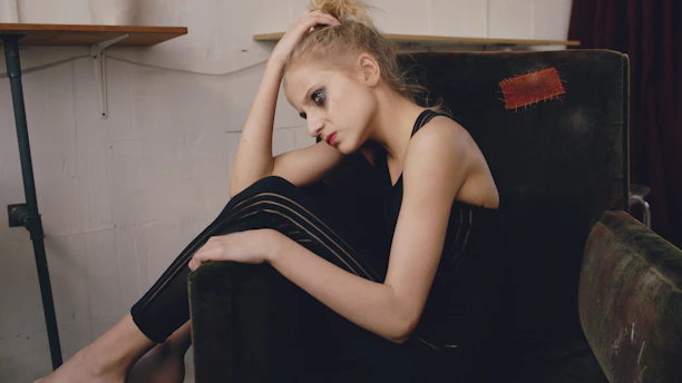 Young woman sitting in a chair with hand on head.