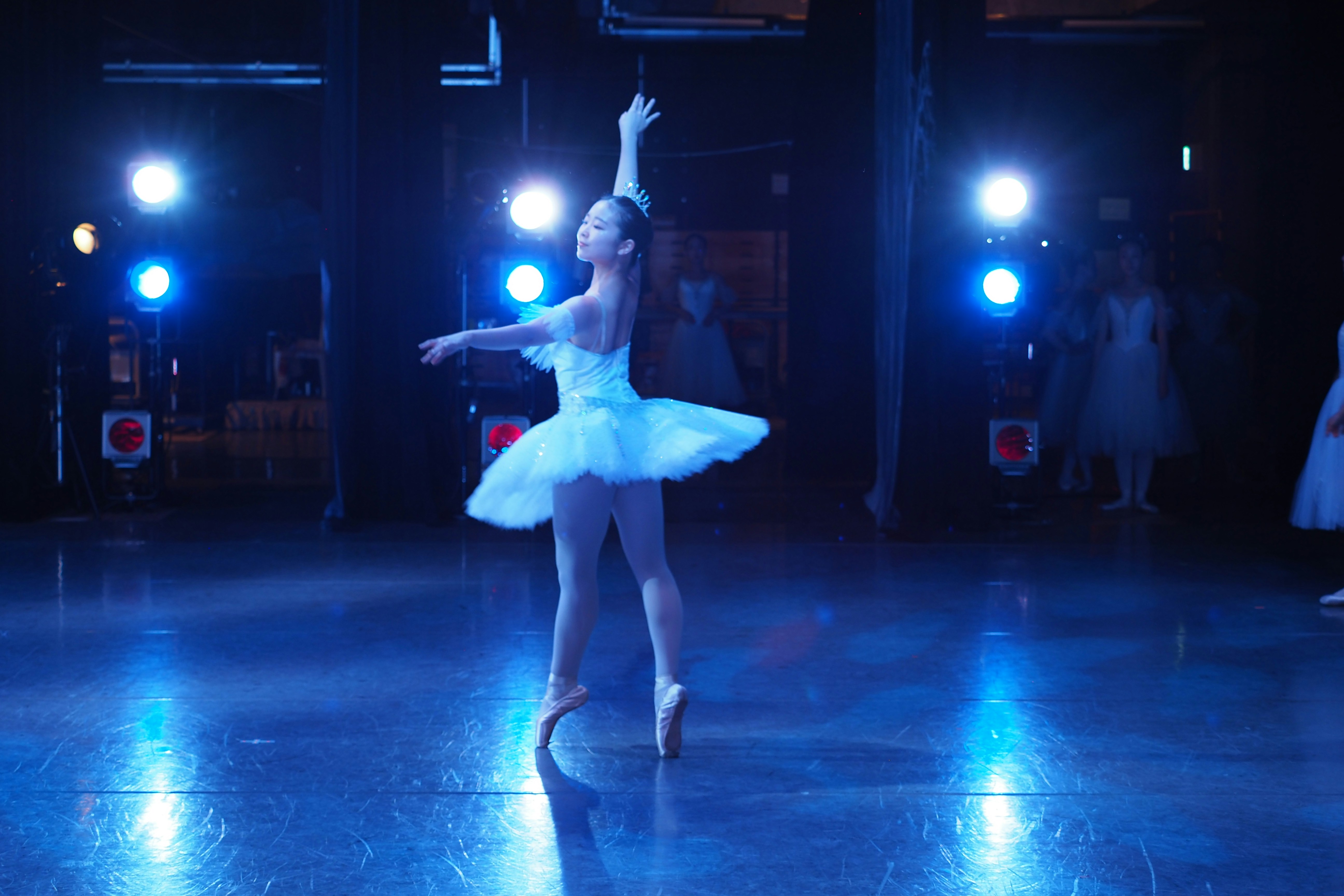 Ballerina performing on a stage with blue lights