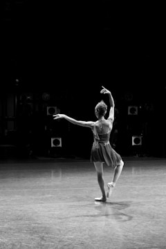 Ballerina performs a graceful pose on a dark stage.