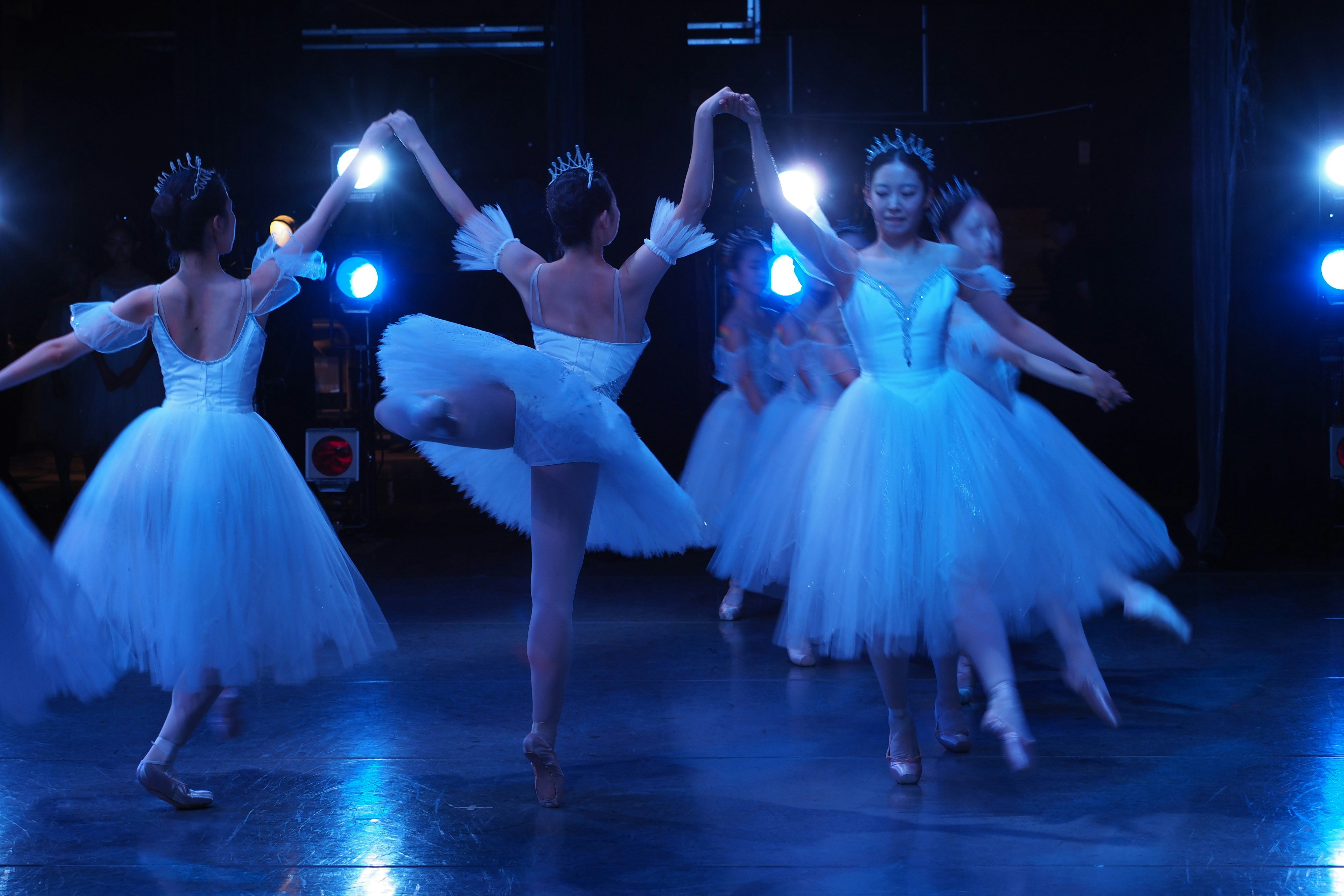 Ballet dancers in white tutus perform on stage